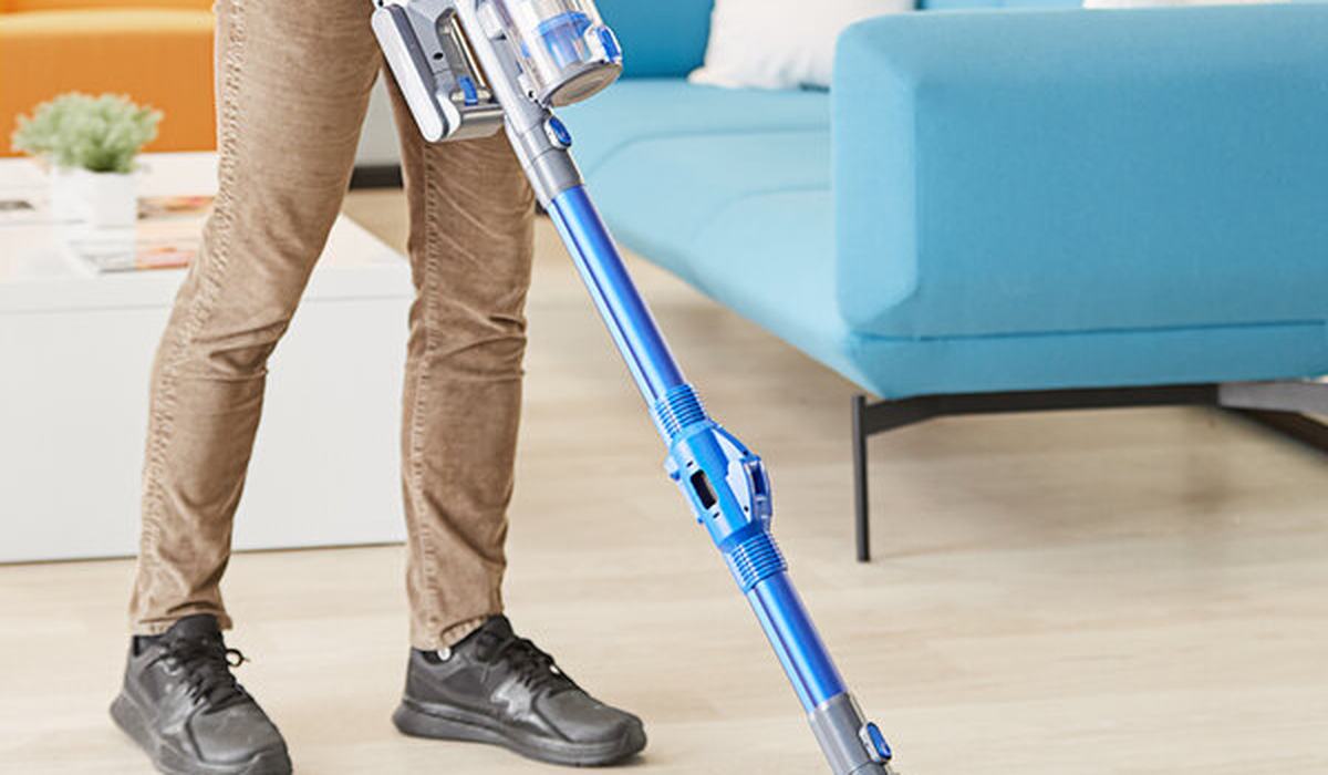 Cordless stick vacuum cleaning a laminate floor in an apartment